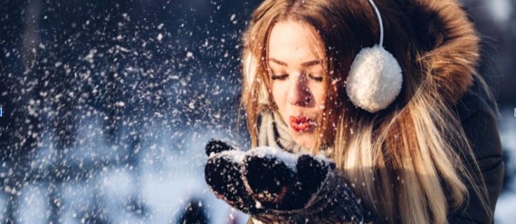 Image of a happy woman playing in the snow outside, conquering the winter blues.